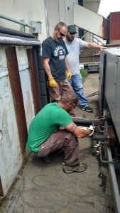 HVAC students from Northeast Technical Institute working at Debesta Pizza to install new equipment. Three students looking over the pipes.