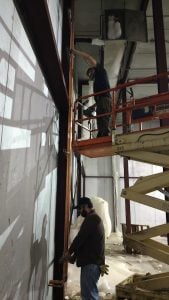 HVAC students from Northeast Technical Institute working at Debesta Pizza to install new equipment. In this picture, one student is on the ground and the other is on a scissor lift.